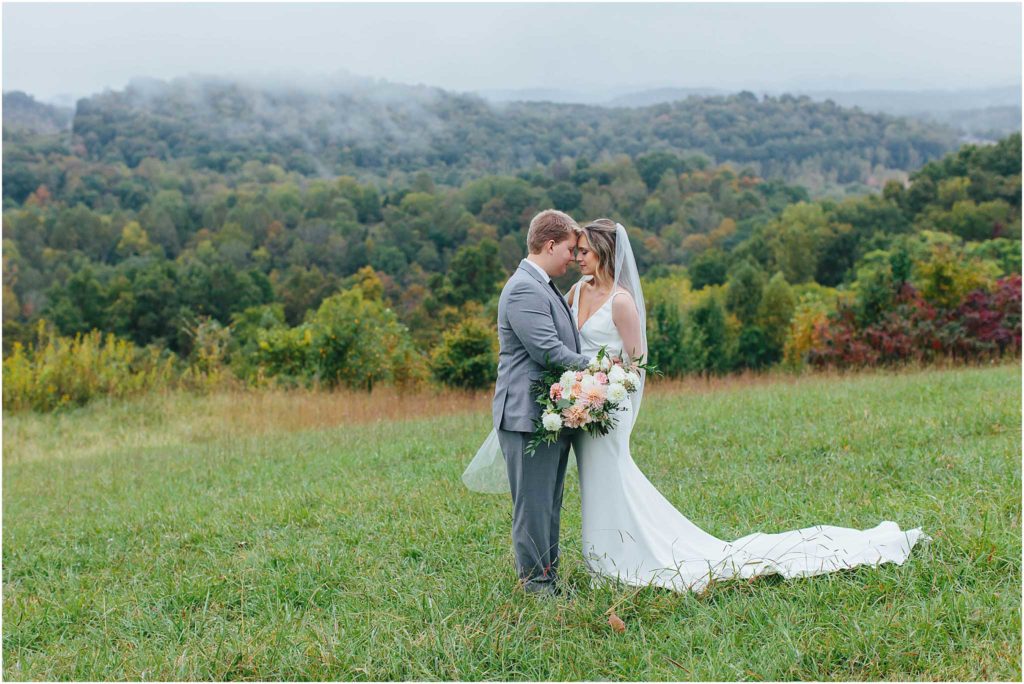 Bride and groom embracing and touching foreheads with foggy mountains in background at chateau selah wedding venue