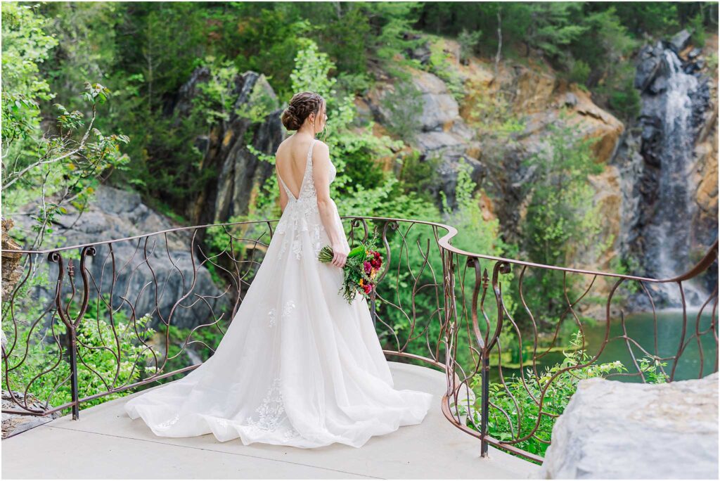 Bride looking at waterstone venue waterfall surrounded by greenery 