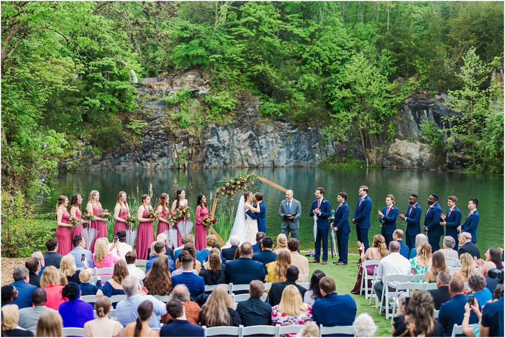 Wide angle view bride and grooms first kiss of lake at waterstone venue ceremony