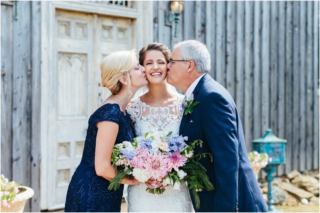 Mother and father kissing brides cheek on wedding day smiling at wedding photographer at Butler TN Crooked River Farm Wedding Venue photography taken by Bristol Virginia Wedding Photographer
