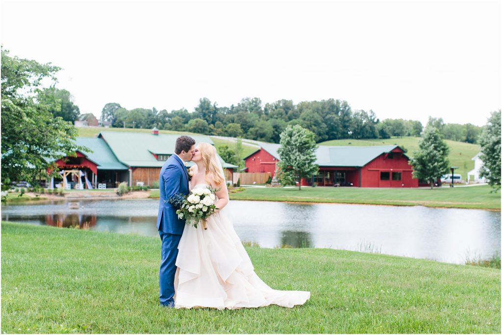 Bride and groom kissing with Grace Meadows Farm wedding venue in the background