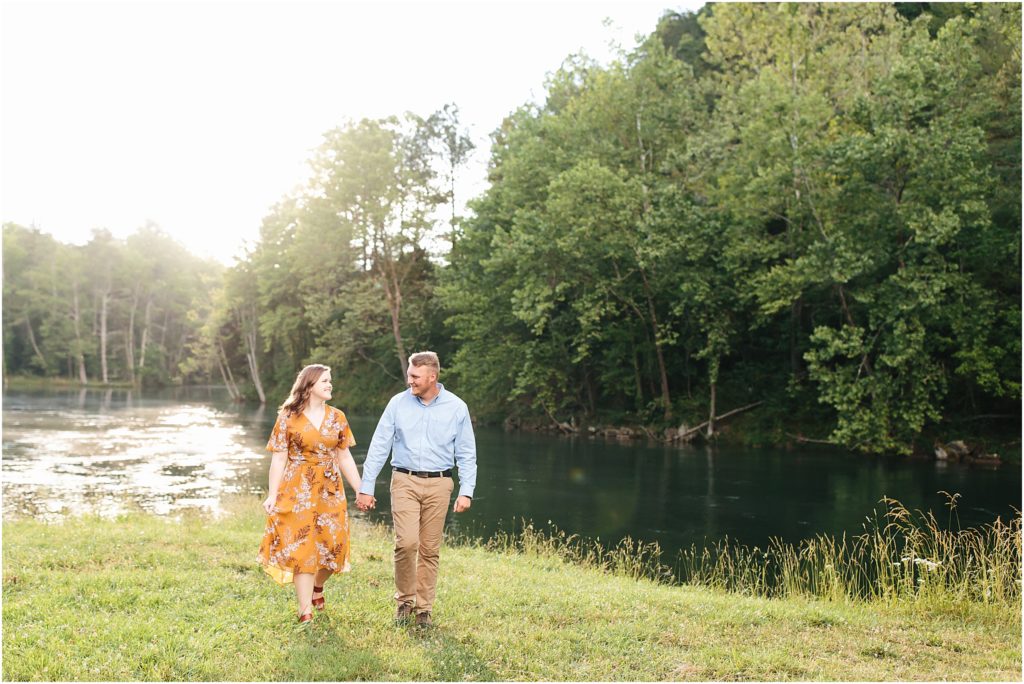 engaged couple walking in open field at south holston dam