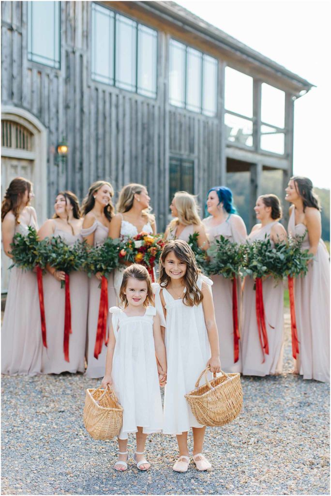 Flower girls smiling in focus while bridesmaids in the background laugh and talk. Taken at hiltons va crooked river farm venue