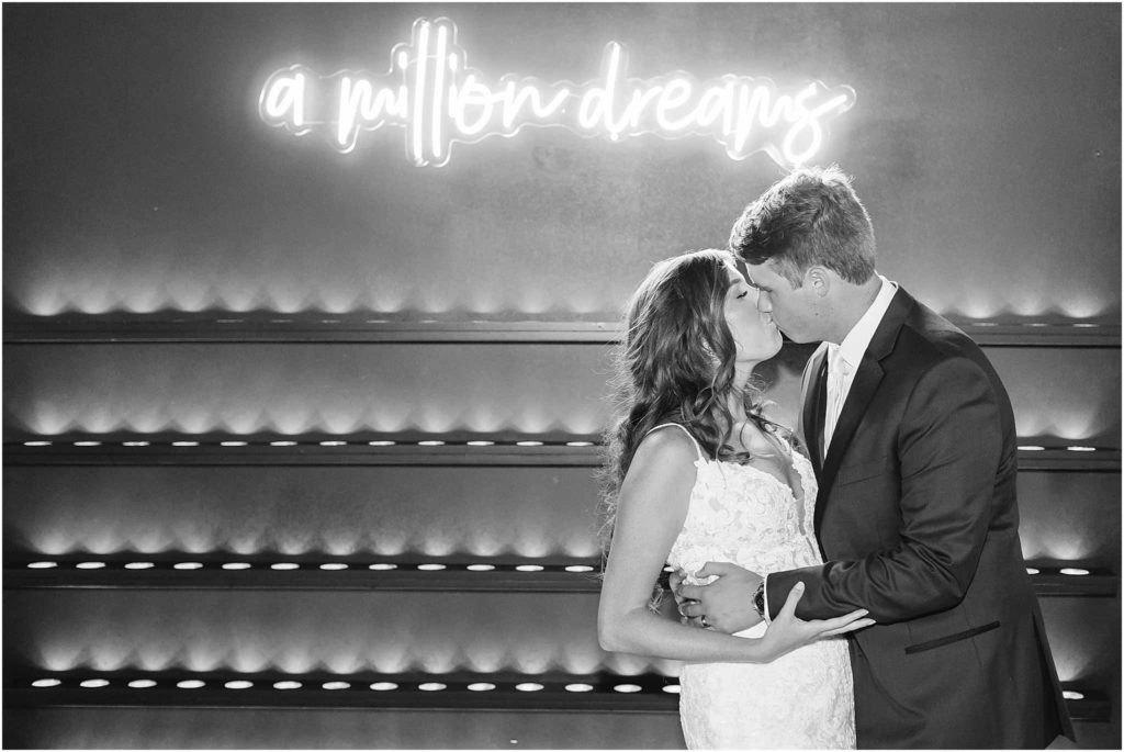 Bride and groom kiss in front of neon lights