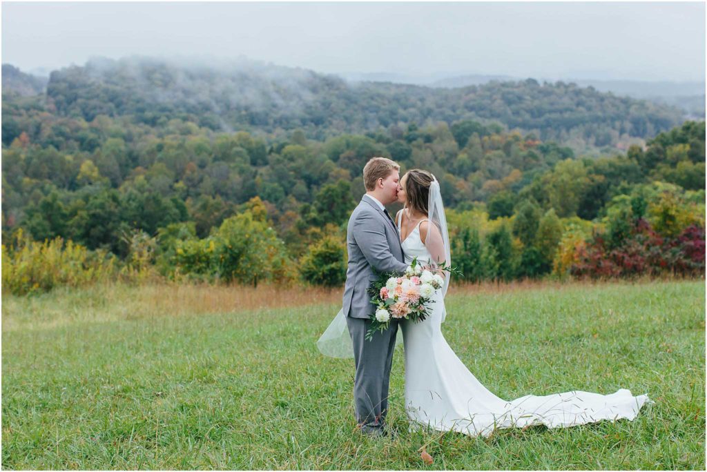 Bride and groom sharing kiss with foggy mountains in background at chateau selah wedding venue in blountville tn