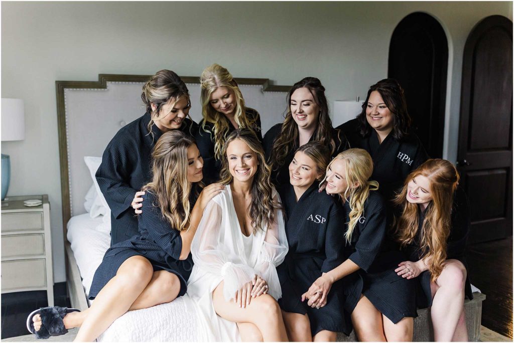 Bride sitting on bed surrounded by her bridesmaids posing for Chateau Selah wedding photographer