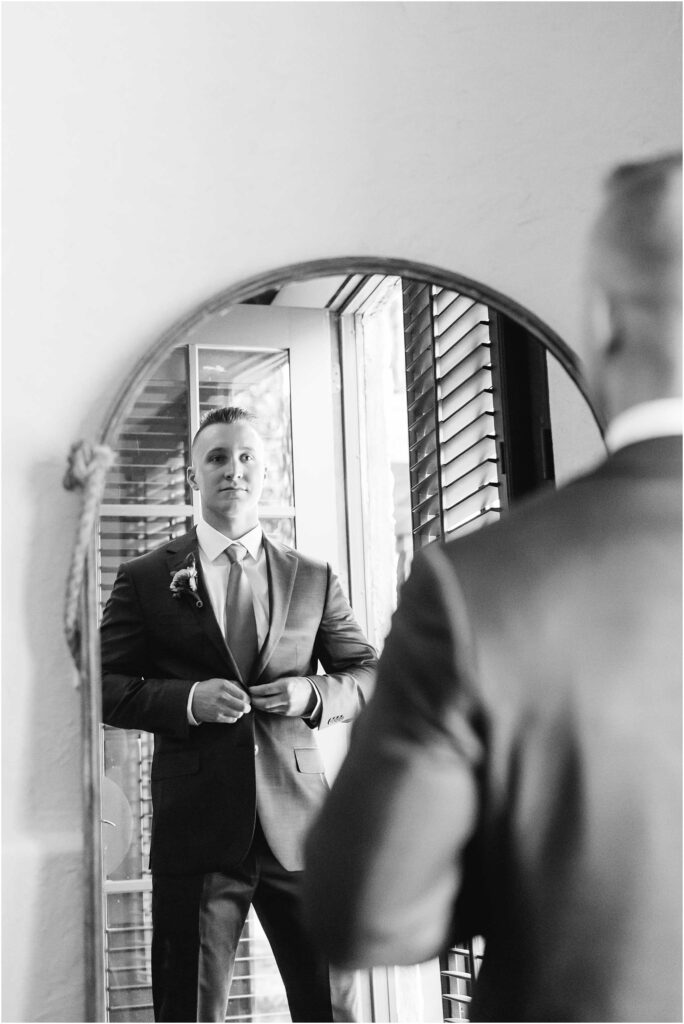 Groom buttons suit in mirror in johnson city wedding venue